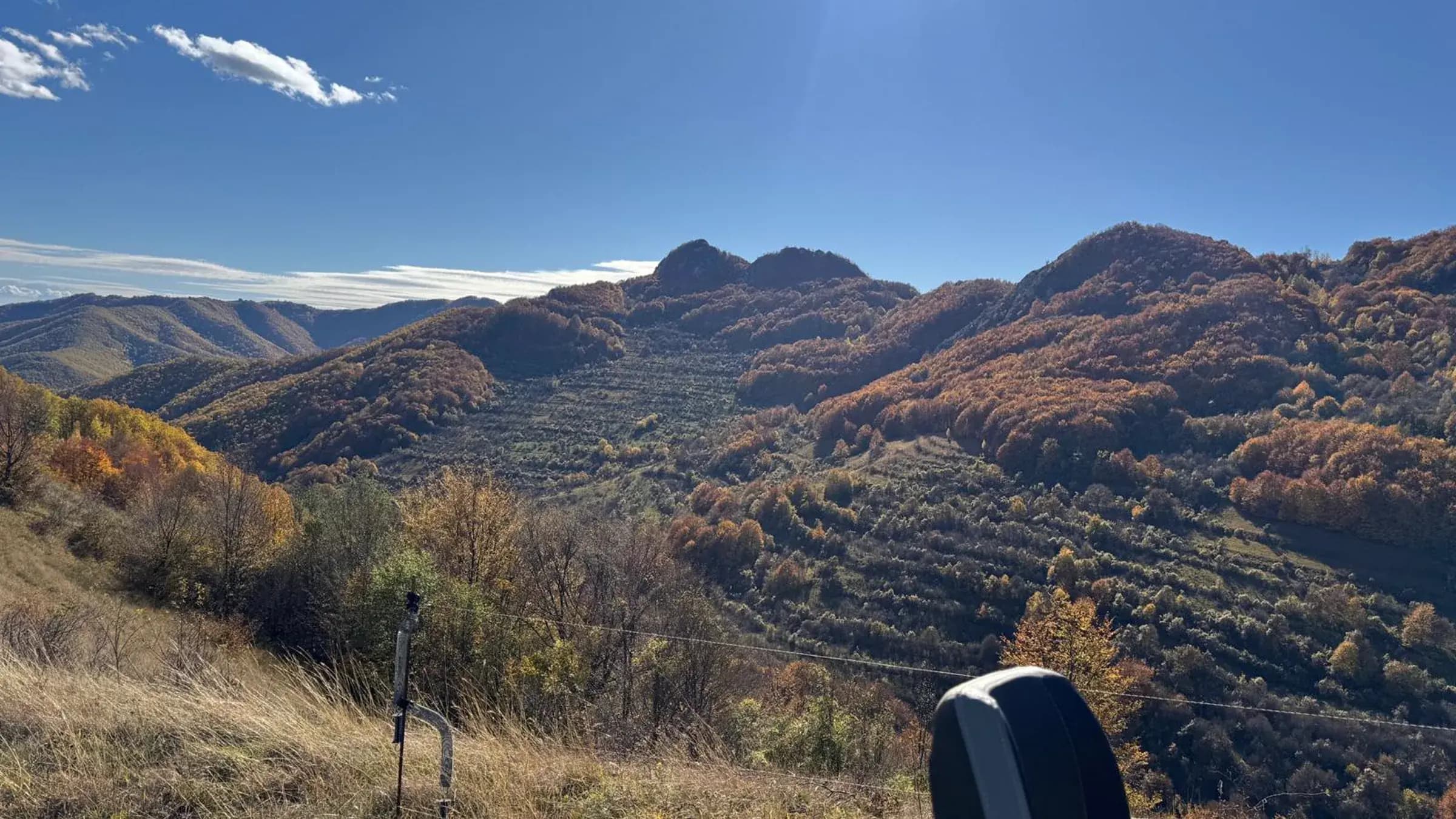 A rider overlooking a terraced autumn valley from a mountain ridge
