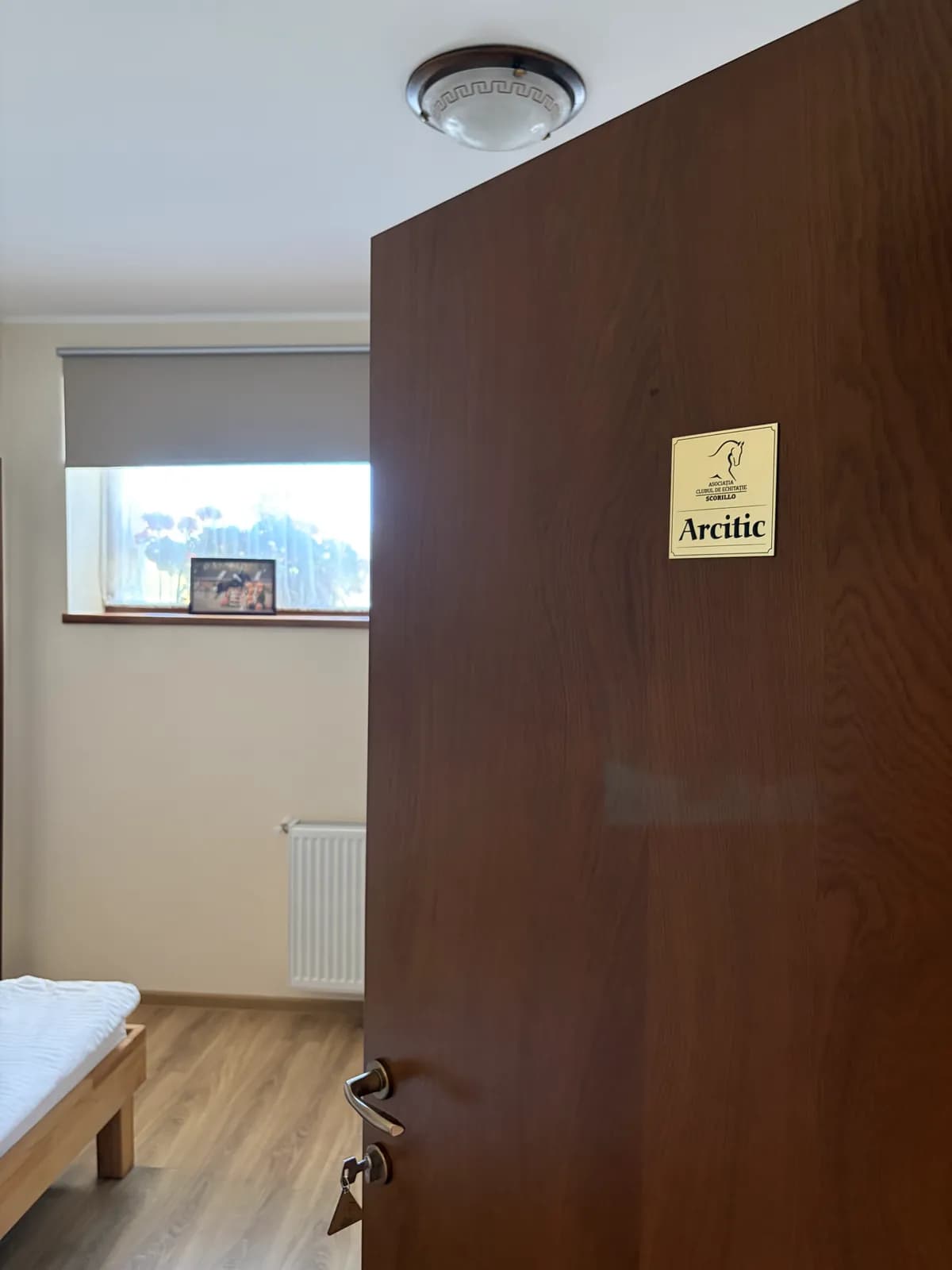 A wooden door opening onto a bright room, an engraved brass plaque reading Arcitic on the door