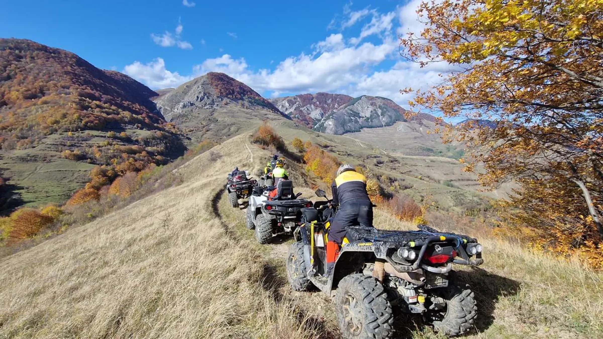 Convoy of ATVs silhouetted along an autumn ridge crest