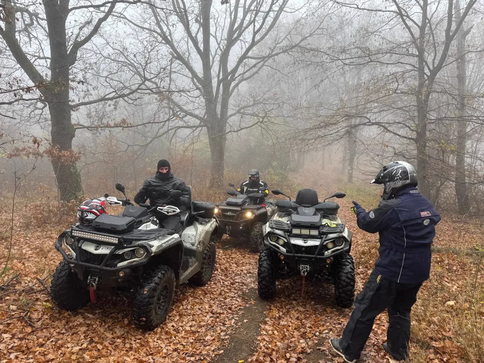 A guide gesturing to three riders on a misty forest trail